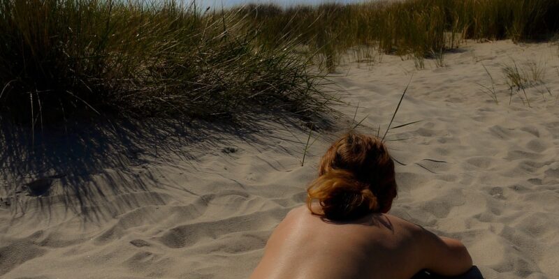 Woman lying on her front while sunbathing naked on a beach